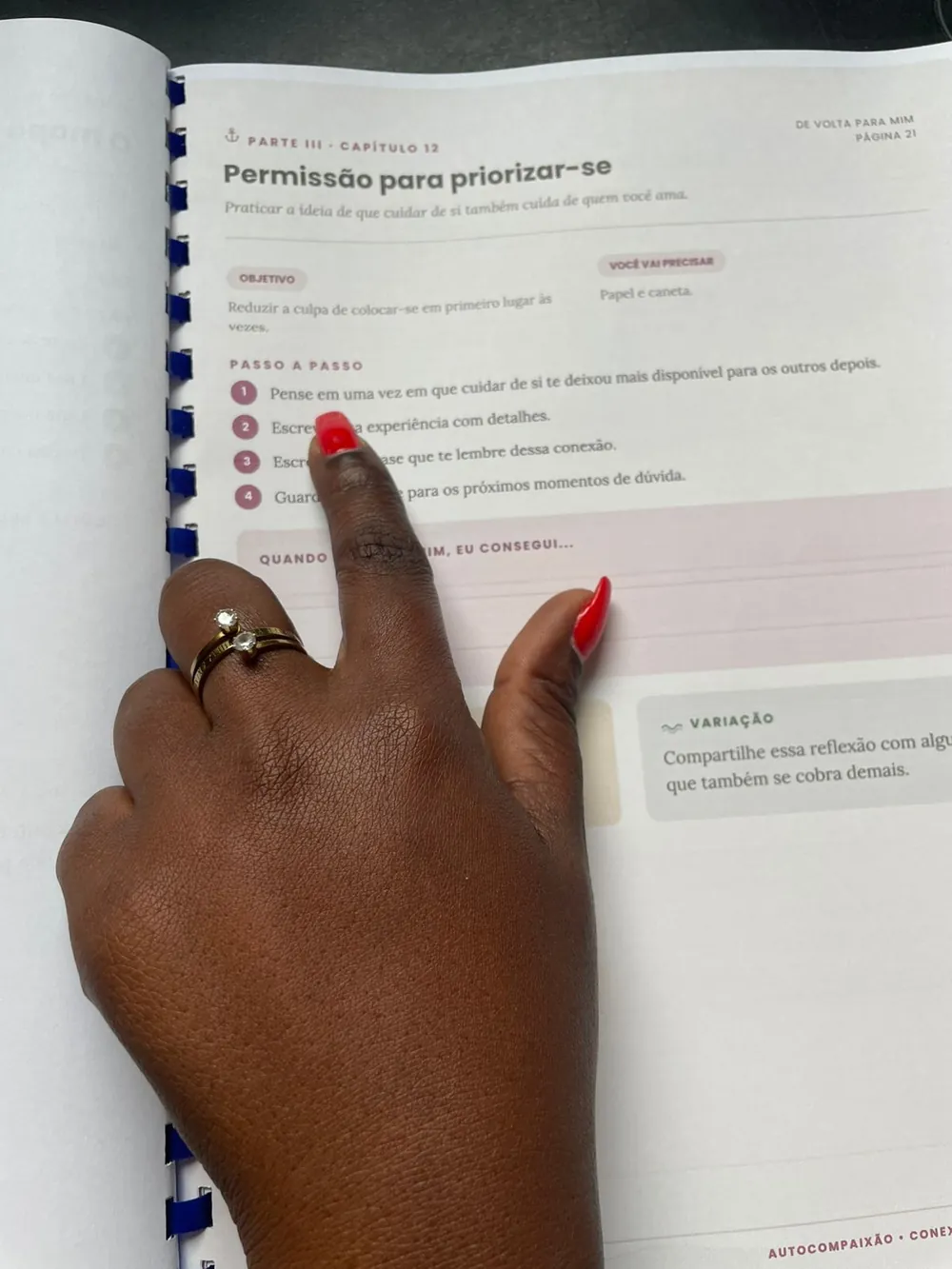 Foto real do material De Volta Para Mim aberto, com uma caneta durante um exercício escrito